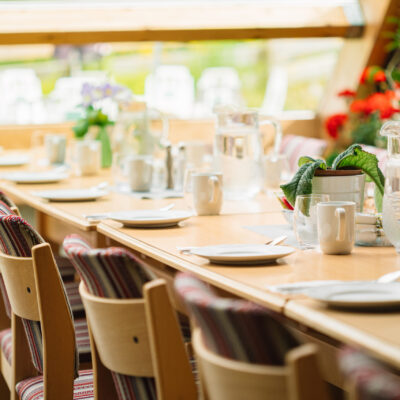 Cozy Interior Of Summer Cafe. Jug Of Water On Table And Cutlery Laid Out.