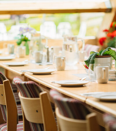 Cozy Interior Of Summer Cafe. Jug Of Water On Table And Cutlery Laid Out.